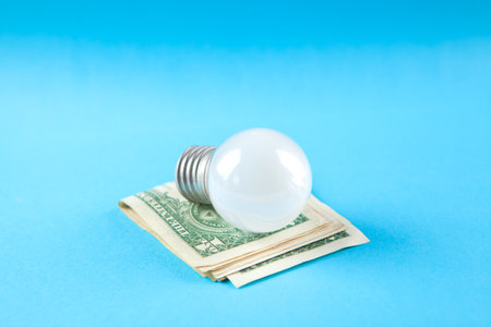 light bulb and money on blue backgroundの写真素材