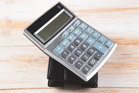 calculator on wallet on wooden background