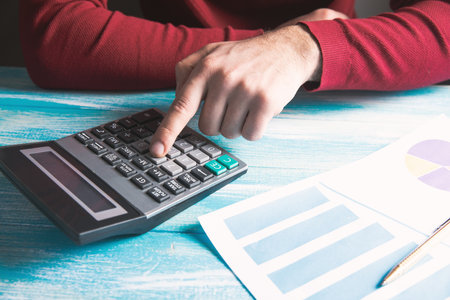 looks at charts and calculates with a calculator on the tableの写真素材