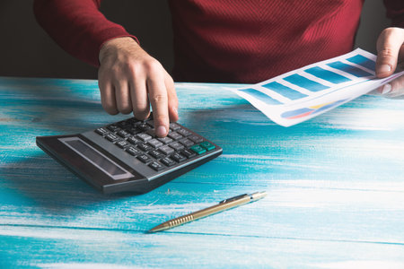 looks at charts and calculates with a calculator on the tableの写真素材