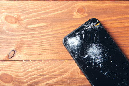 broken smartphone screen on wooden background
