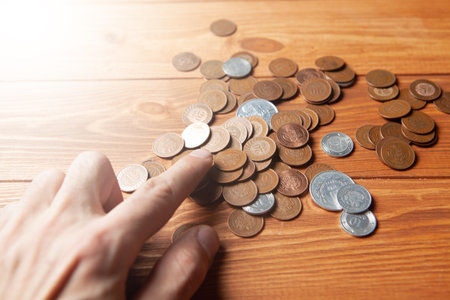 man counting coins on wooden table