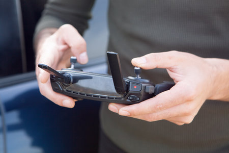a man controls the drone's remote control during the day