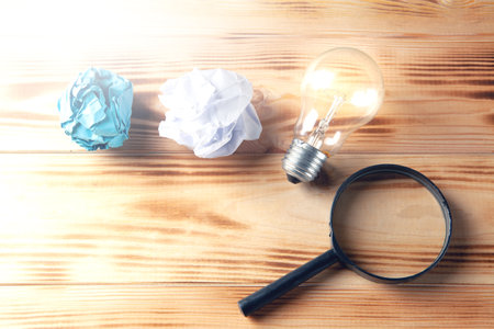concept study go. Lamp, crumpled papers and a magnifying glass on the table.の写真素材