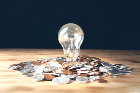 glowing lamp and coins on a dark backgroundの写真素材