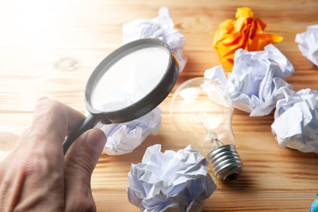 concept study go. Lamp, crumpled papers and a magnifying glass on the table.の写真素材