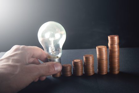 glowing lamp and coins in the form of diagrams on a dark backgroundの写真素材
