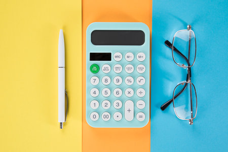 on the desktop calculator, pen and glasses. multicolored paperの写真素材