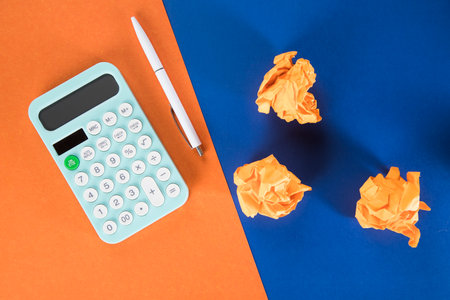 calculator and wads of papers on the desktop. costing concept