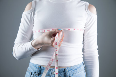 young girl measures breast girth on a gray backgroundの写真素材