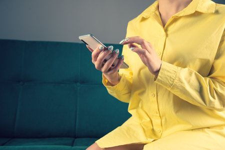 a young girl in a yellow jam keeps her phone sitting on the couchの写真素材