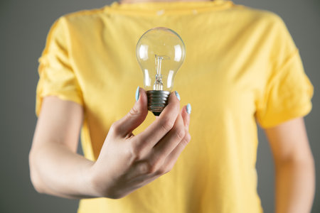 a girl in a yellow dress holding a light bulb