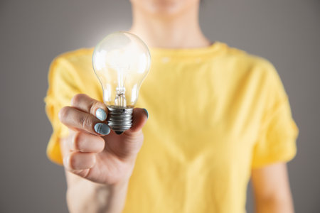 a girl in a yellow dress holding a light bulbの写真素材