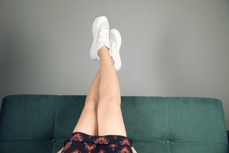at home on a green sofa, women's legs are raised highの写真素材