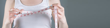 young girl measures breast girth on a gray background
