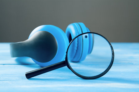 headphones and loupes. audio file search concept on blue wooden background