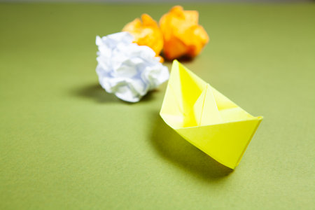 yellow paper boats and reams of paper on green background