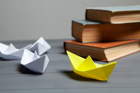 white boats go for yellow next to books on a gray background