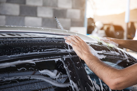 a man wipes the foam on the car with a rag. car washの写真素材