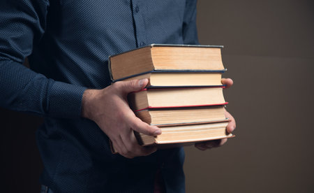 man holding books in his hands on brown background