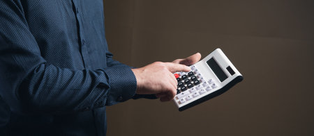 a man in a shirt is counting on a calculator on a brown background