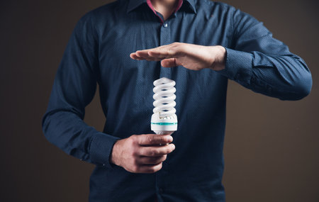 man holding ecological light bulb on brown background