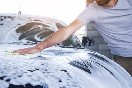 a man wipes the foam on the car with a rag. car washの写真素材