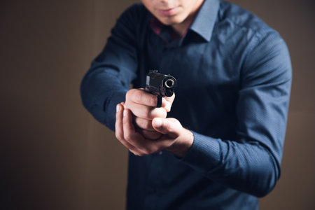 a man holding a black pistol in his hand threateningの写真素材
