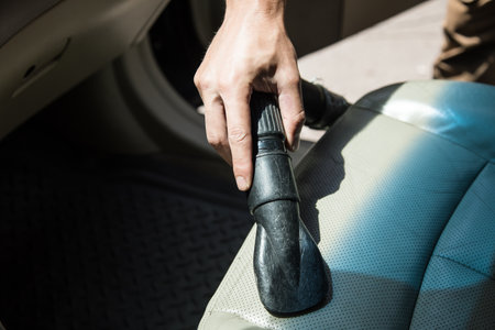 man vacuums the car seat. Cleaning in the carの写真素材