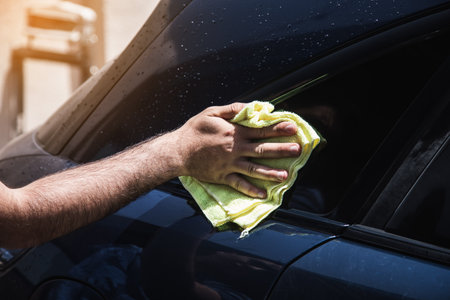 a man wipes a wet car with a ragの写真素材