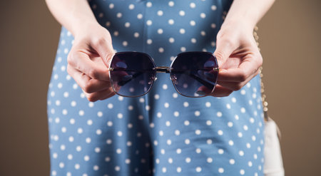 young woman posing holding sunglassesの写真素材