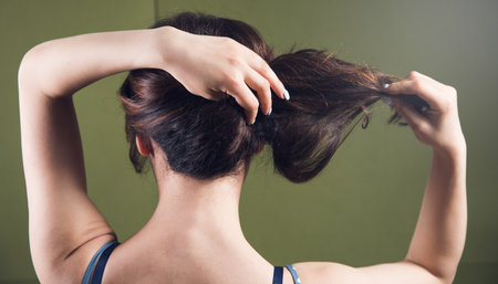 young woman straightens her hair with her handsの写真素材