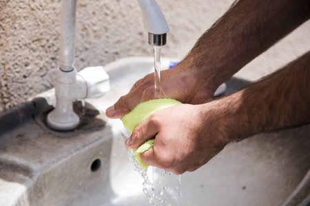 a man wets a rag by the tapの写真素材