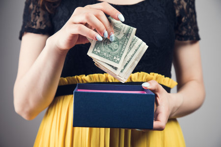 young woman pulls money out of a gift box