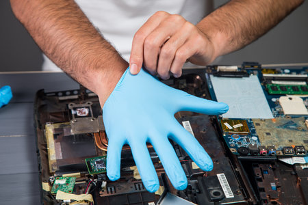 a man puts on a glove before working with microcircuits on a gray backgroundの写真素材