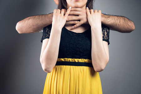 husband strangles wife on gray backgroundの写真素材