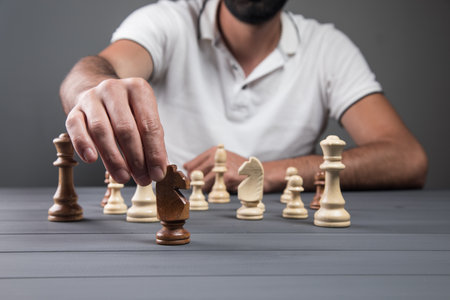 view of a man holding a chess piece in his hand on a gray backgroundの写真素材