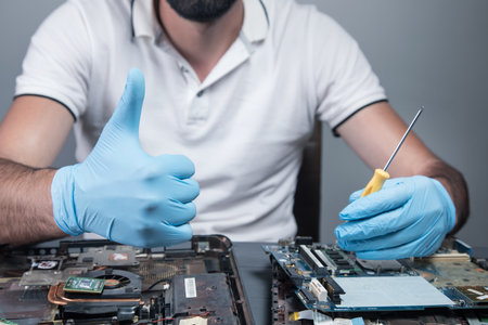 a man disassembles a laptop on a gray backgroundの写真素材