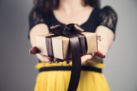 Young girl with gift box on gray backgroundの写真素材