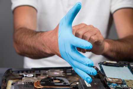 a man puts on a glove before working with microcircuits on a gray backgroundの写真素材