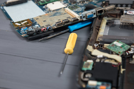 disassembled laptop and tools on grey desk