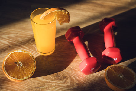 dumbbell, orange and orange juice on the tableの写真素材