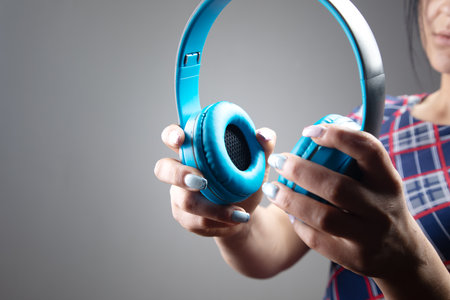 woman holding big headphones on gray background