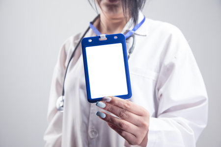 female doctor holding ID tag on gray background
