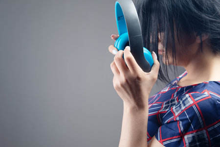 woman holding big headphones on gray backgroundの写真素材