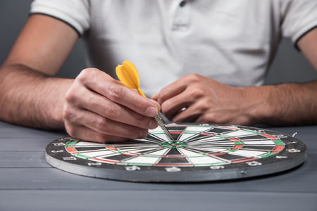 the man puts the dart in the center of the dart board. goal execution concept on gray background