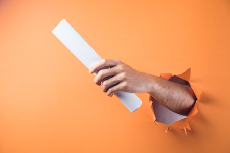 Hand holds paper on orange backgroundの写真素材