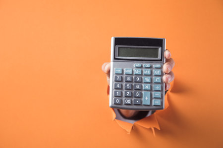 Hand holds calculator on orange backgroundの写真素材