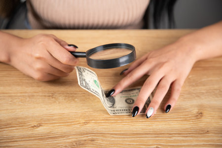 woman checking a dollar bill with a magnifying glassの写真素材
