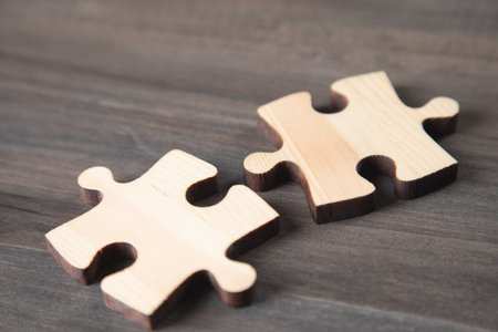 two puzzle pieces on a wooden tableの写真素材